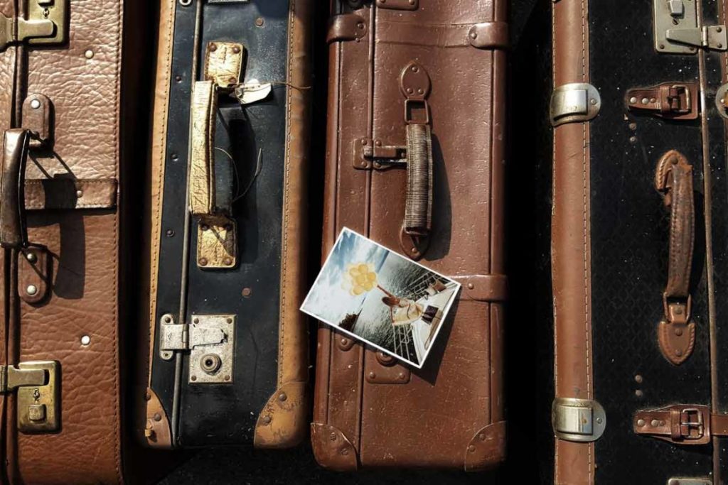Vintage suitcase with a postcard on top.