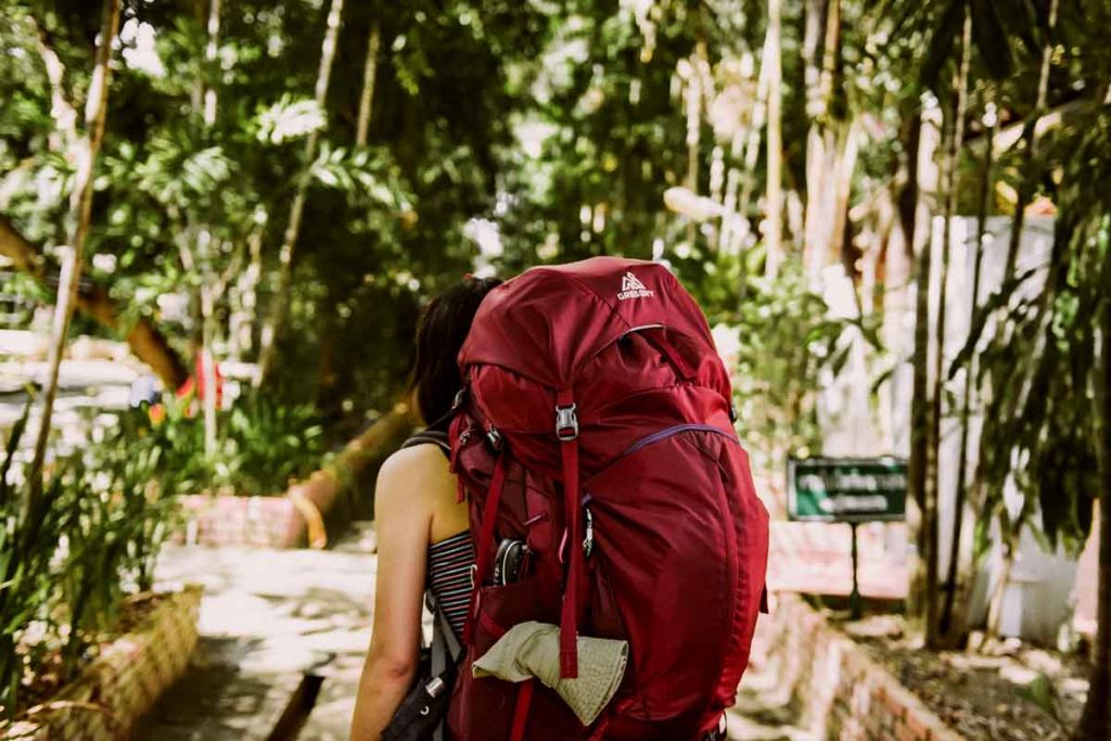 Woman with packed backpack on a budget travel trip 