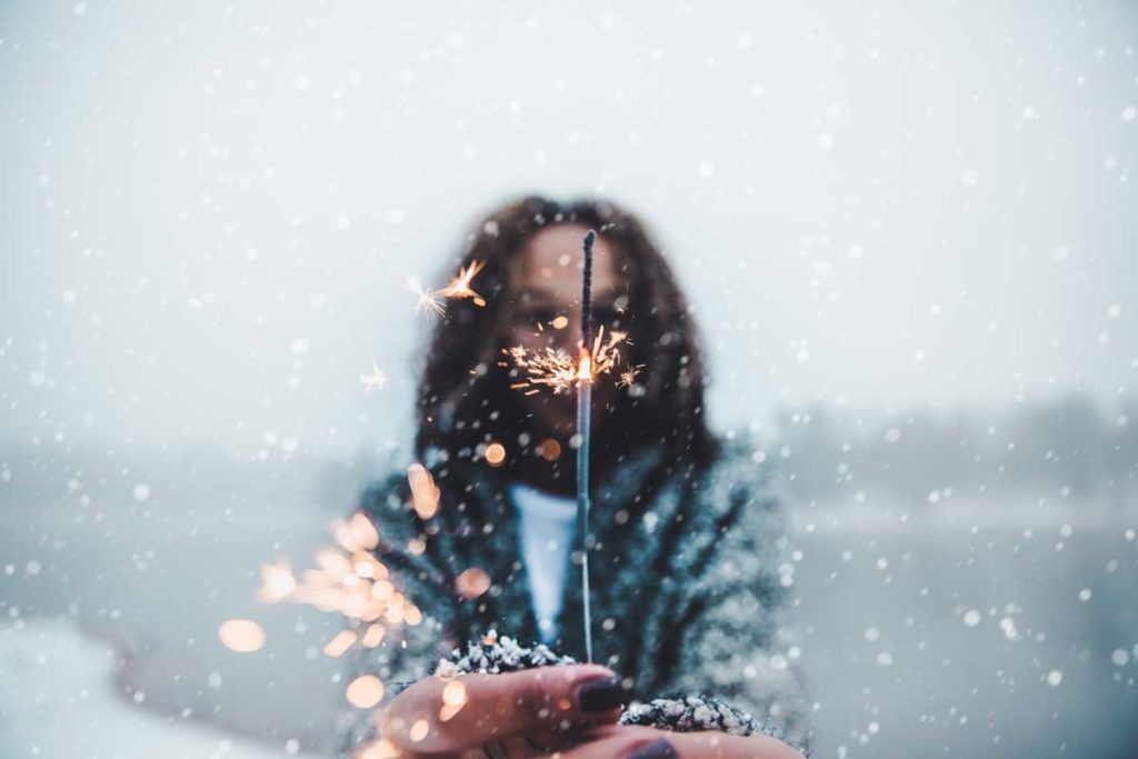Woman holding a sparkler in the snowfall
