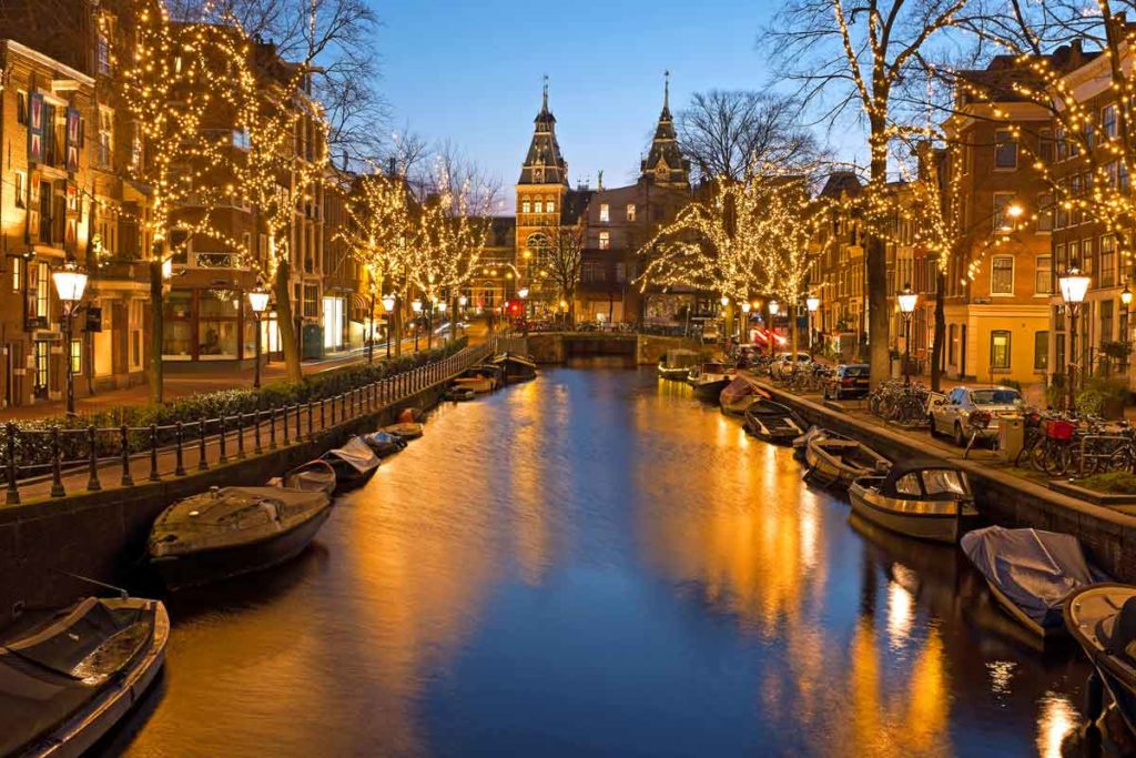 Weihnachtlich beleuchteter Kanal mit Booten in Amsterdam, Niederlande