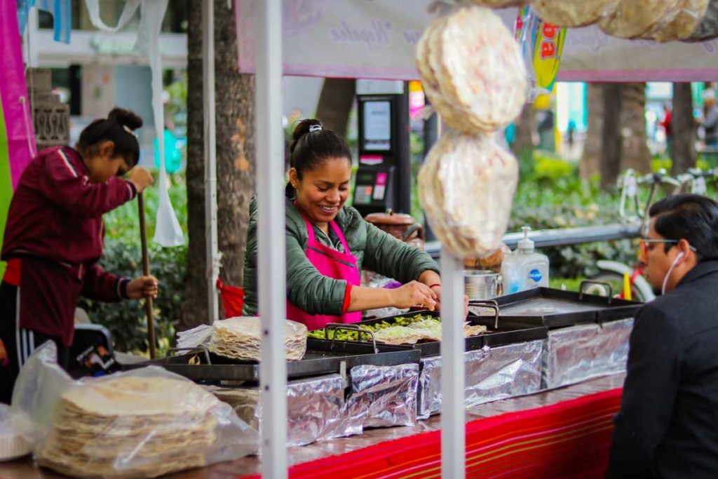 Woman prepares traditional mexican food in street market