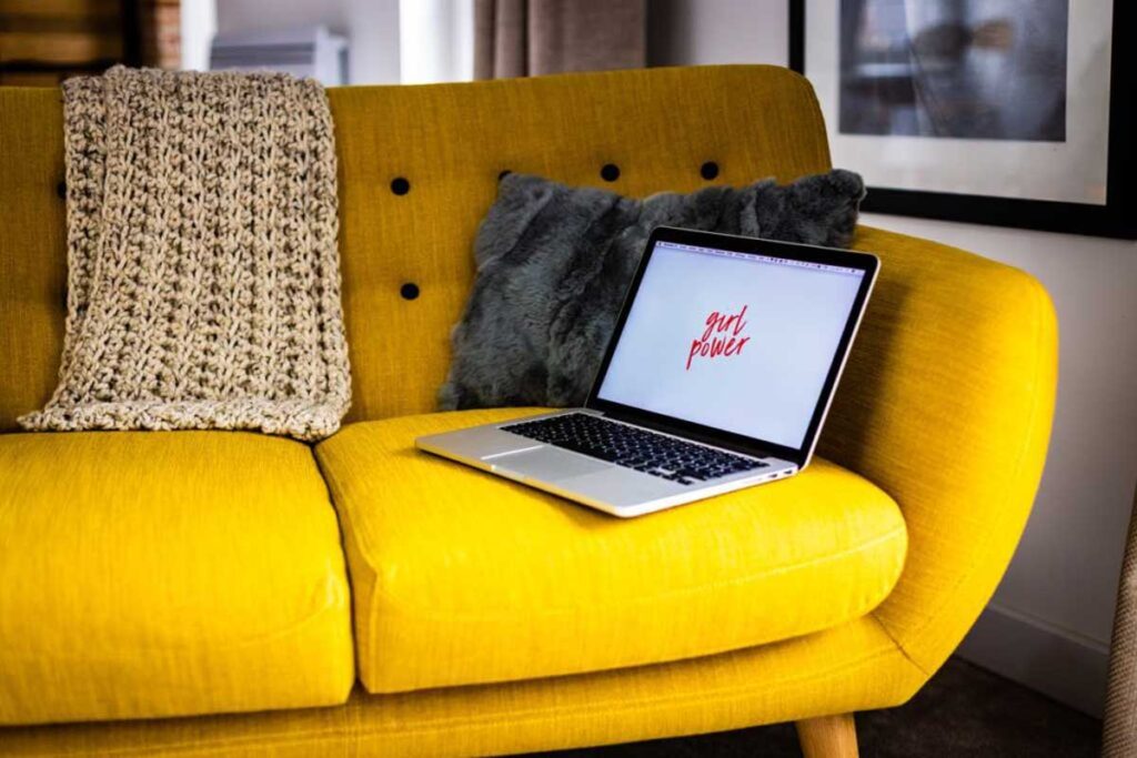Laptop waits on a yellow sofa encouraging us to stay social through girl power