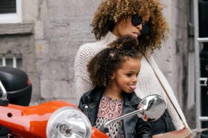 Eine Mutter und Tochter posieren zusammen neben ein Motorrad.