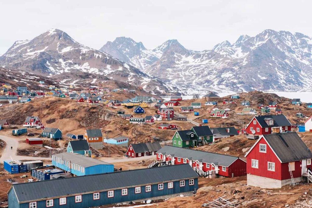A colourful town lies at the foot of snow-topped mountains