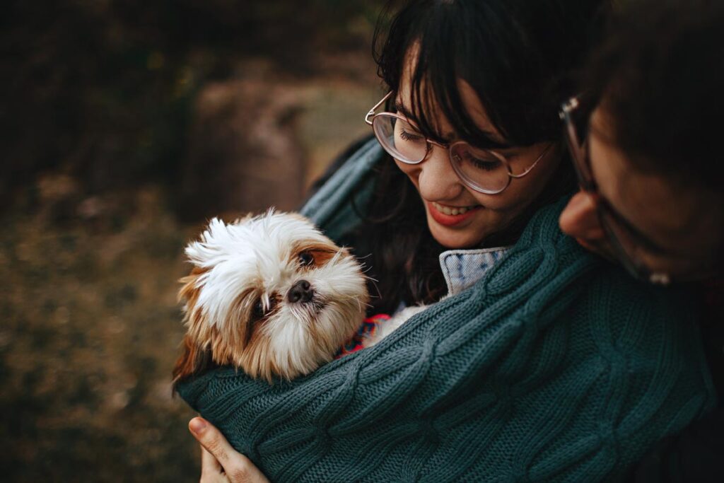 A couple cradle their small dog in a green blanket