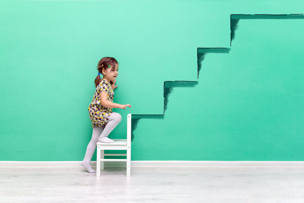 Ein kleines Mädchen klettert an der Wand gemalten Treppen