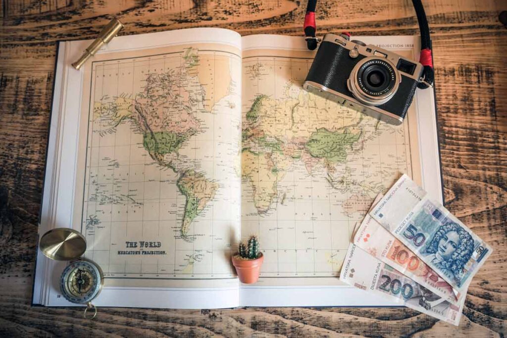 Eine Weltkarte mit Kamera und Geld - starte dein Urlaub zu Hause