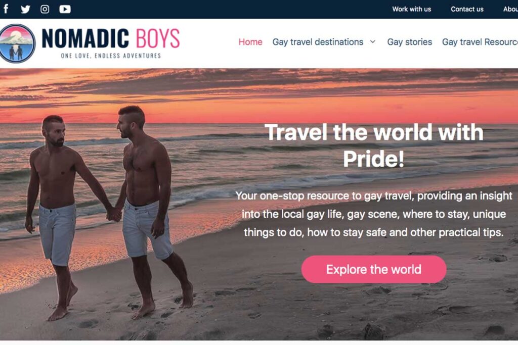 Gay travel bloggers from best LGBT blog Nomadic Boys walk holding hands on the beach