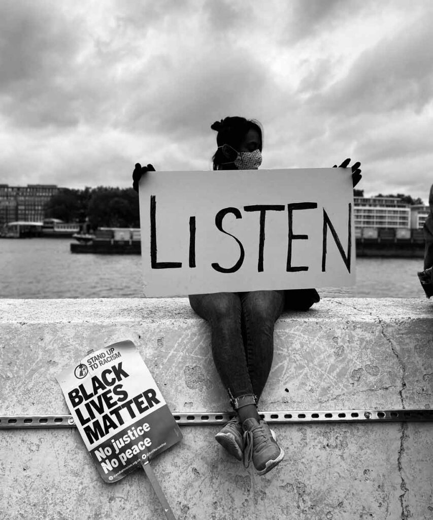A woman protests for BLM saying 'listen' and showing how to be anti-racist