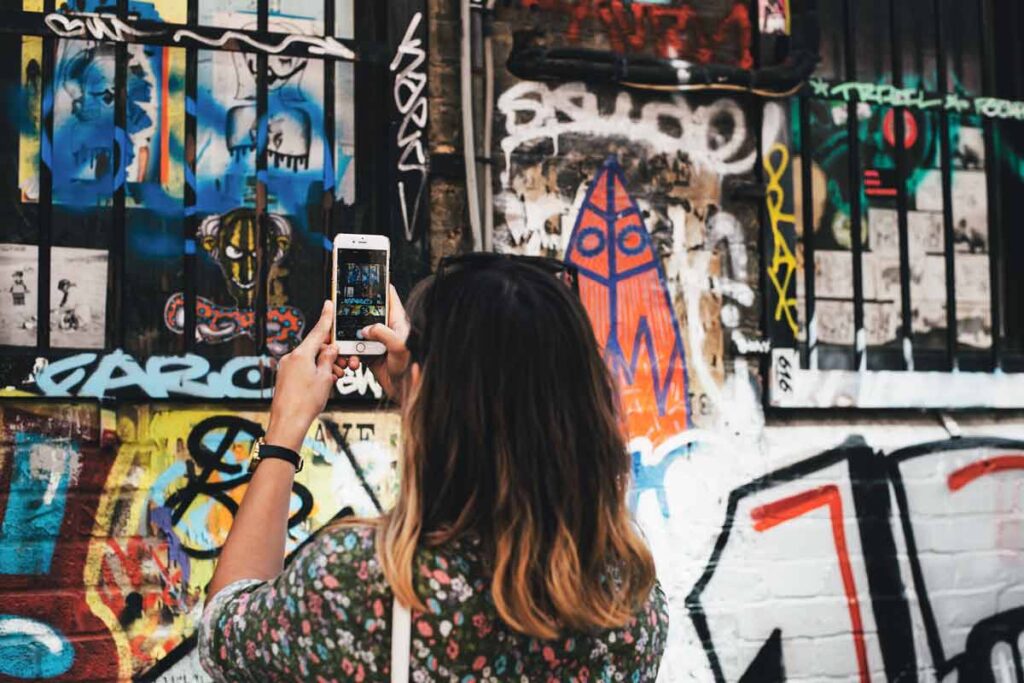 A woman photographs a graffiti wall