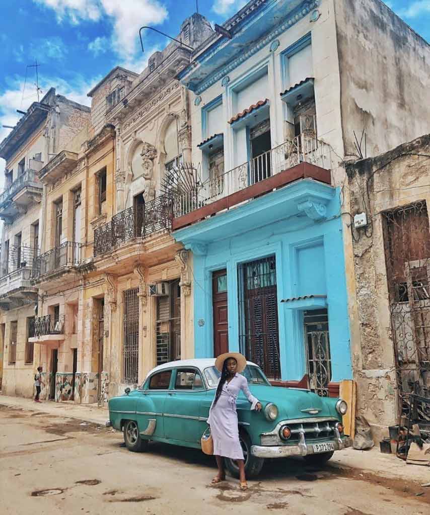Jessica is in front of a colorful set of buildings as she travels while black