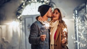 Ein Paar küssen sich am Sylvester mit Wunderkerzen als alternative Silvesteridee