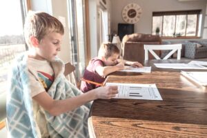Two kids sit do homework as part of their New Year's Resolutions ideas