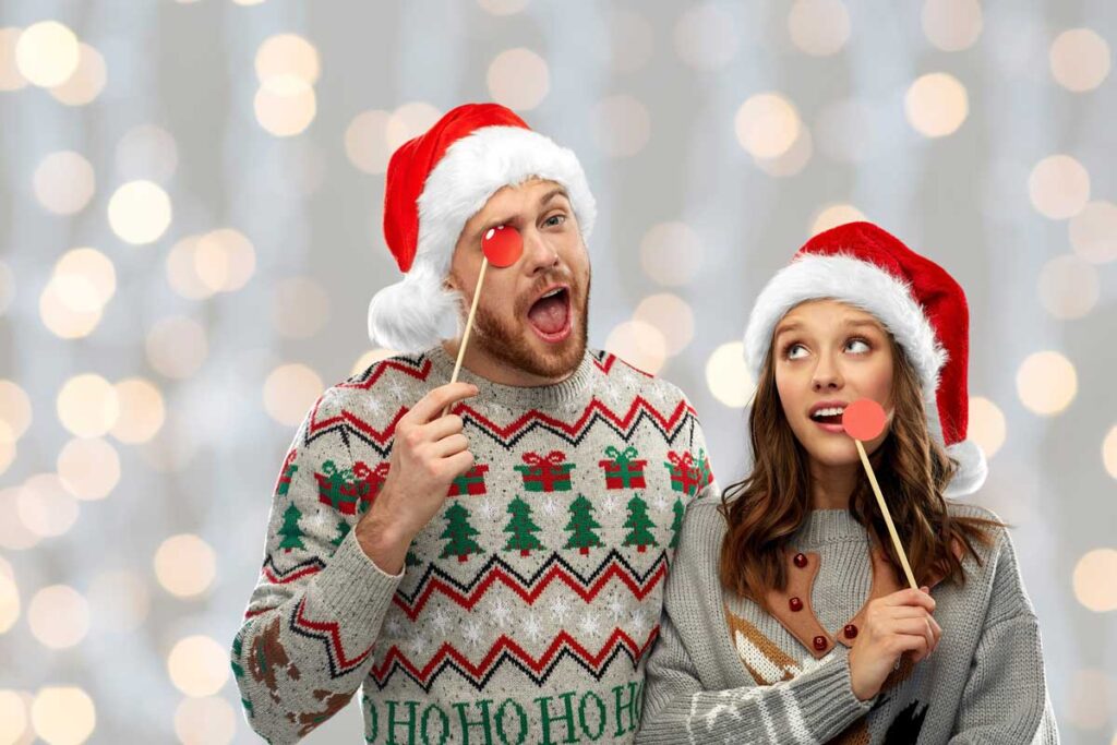 Ein Paar tragen hässliche Weihnachtspullis und Weihnachtsmütze für ein Weihnachtsfoto