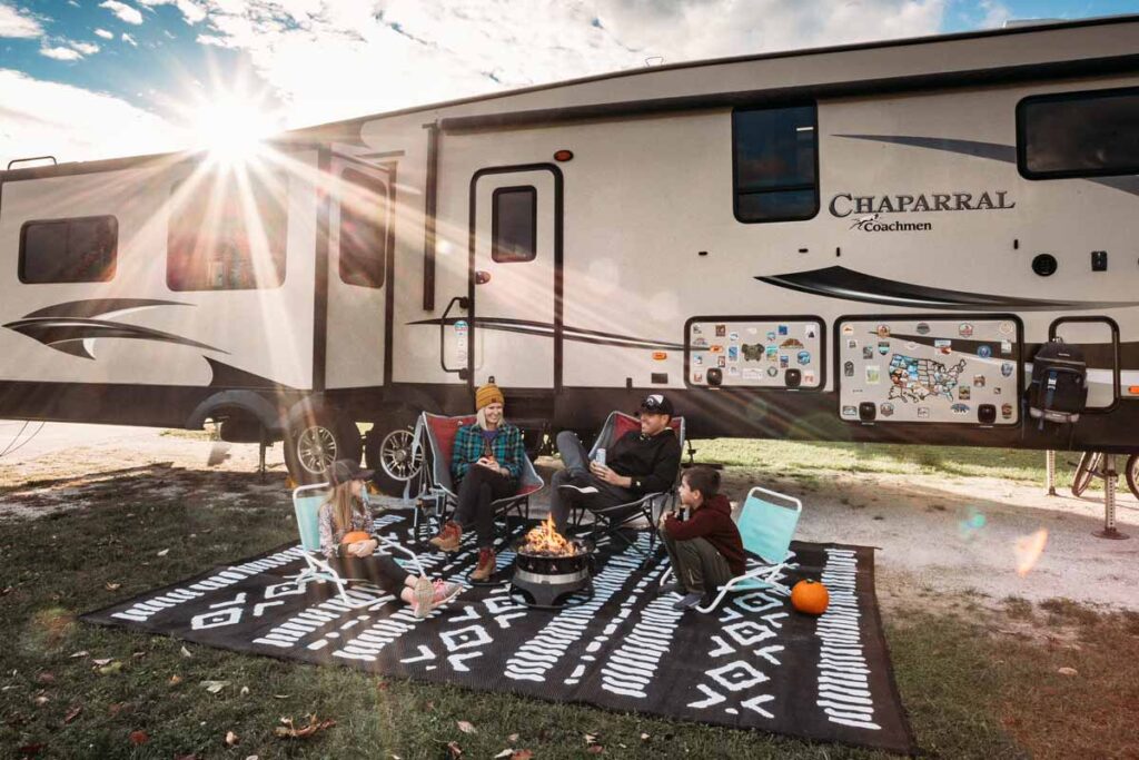 The Wanderpreneur camping blog family  sit on a picknick blanket in front of their caravan
