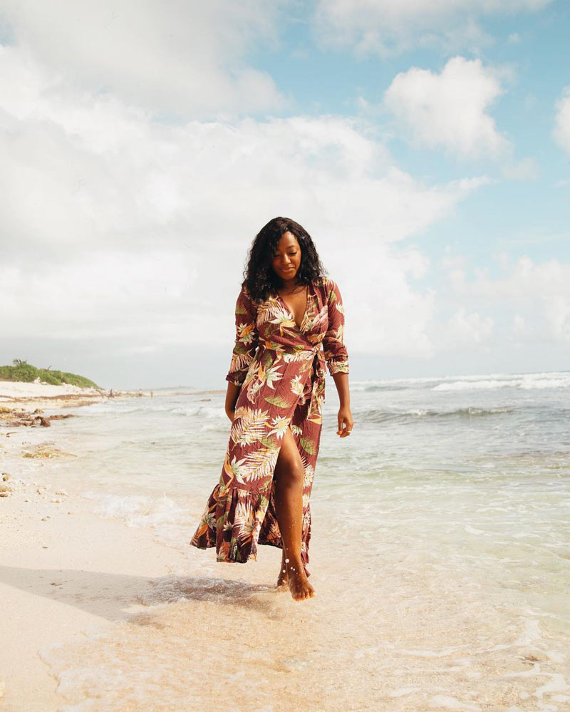 Ciara, a black solo travel influencer to follow, walks on the beach 
