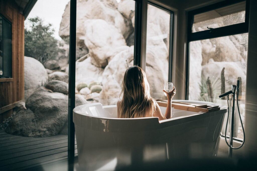 A woman sits in a bath in front of beautiful scenery