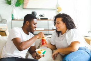 A couple eat take out on the sofa