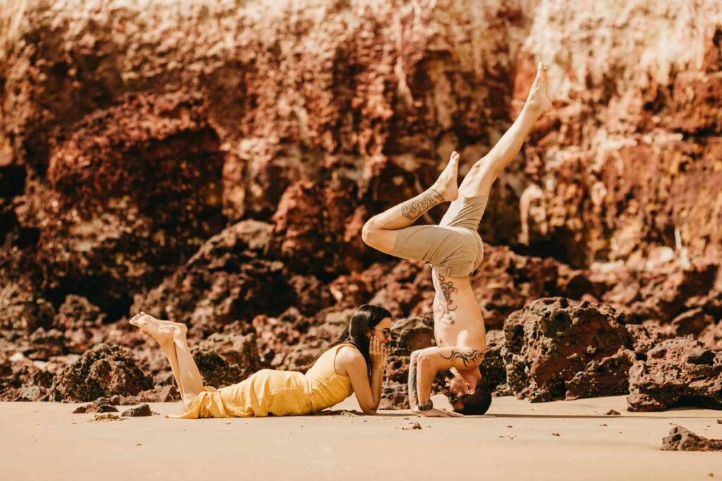 A couple do yoga together on the beach