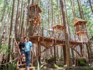 Judy and Pete stand in front of one of their treehouses from the Nelsons' camping blogs