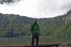 Ein Man steht vor einen See im Wald
