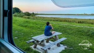 Blogger sitzt auf Tisch und guckt der See an