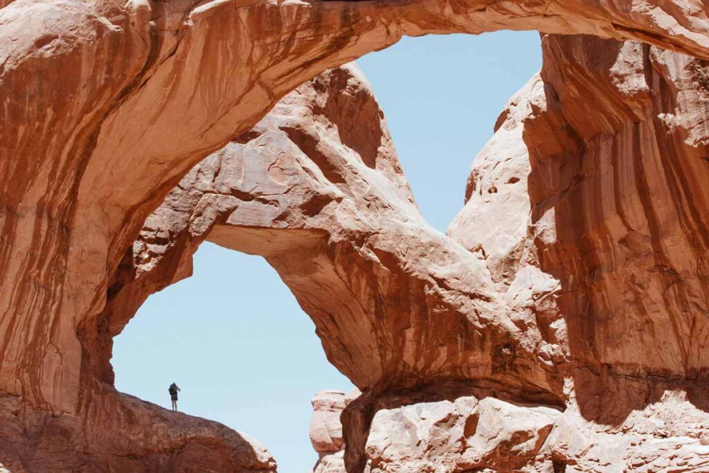 A traveler dwarfed by the inspirational humungous rock formations at Arches National Park