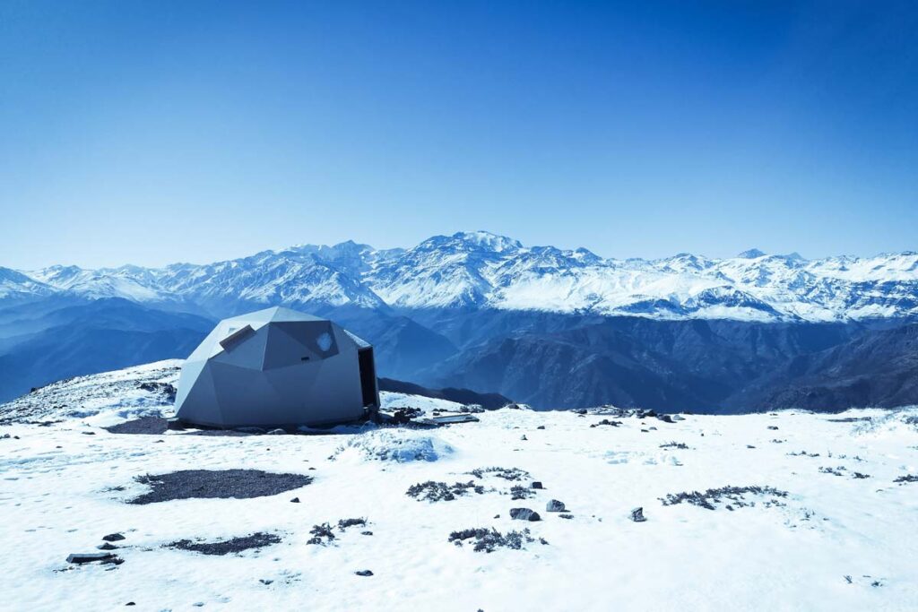 A tent under blue skies in the snow represents the winter type of camping.