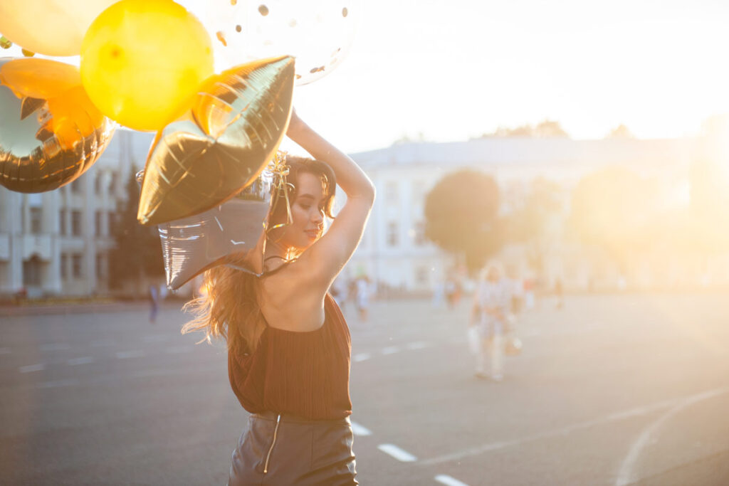 A woman celebrates her 21st milestone birthday holding balloons
