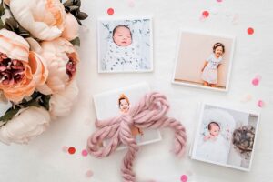 Homemade DIY photo coasters gift idea lying next to flowers, and decorated with a ribbon.