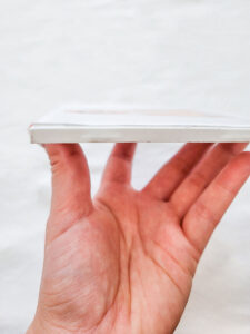 A hand hold up the half made DIY photo coaster against a white background.