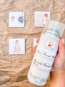 A hand holds up protective spray with the homemade photo coasters in the background.