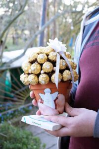 Ein Man haltet den DIY Ferraro Rocher Geschenkbaum und MyPostcard Fotoabzug