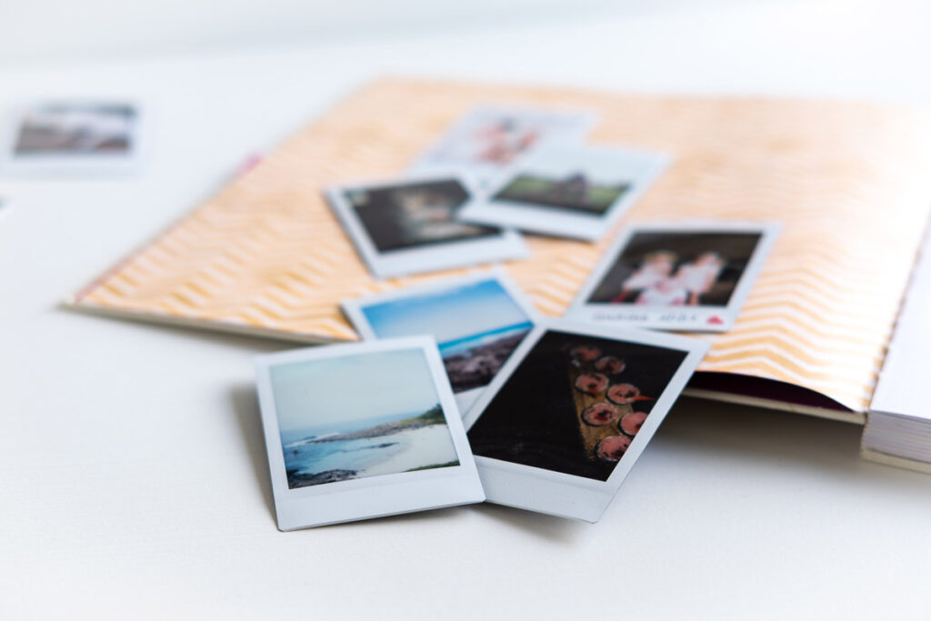 Family polaroid prints lie on top of a blank photo album