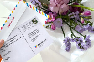 A birthday card lies on the table next to roses, while what to write in it is considered