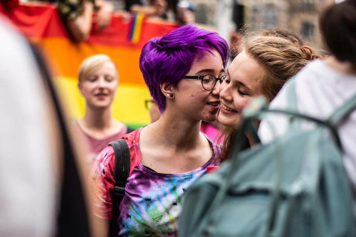 Two members of the LGBTQ+ community kiss during a street parade celebrating Pride Month