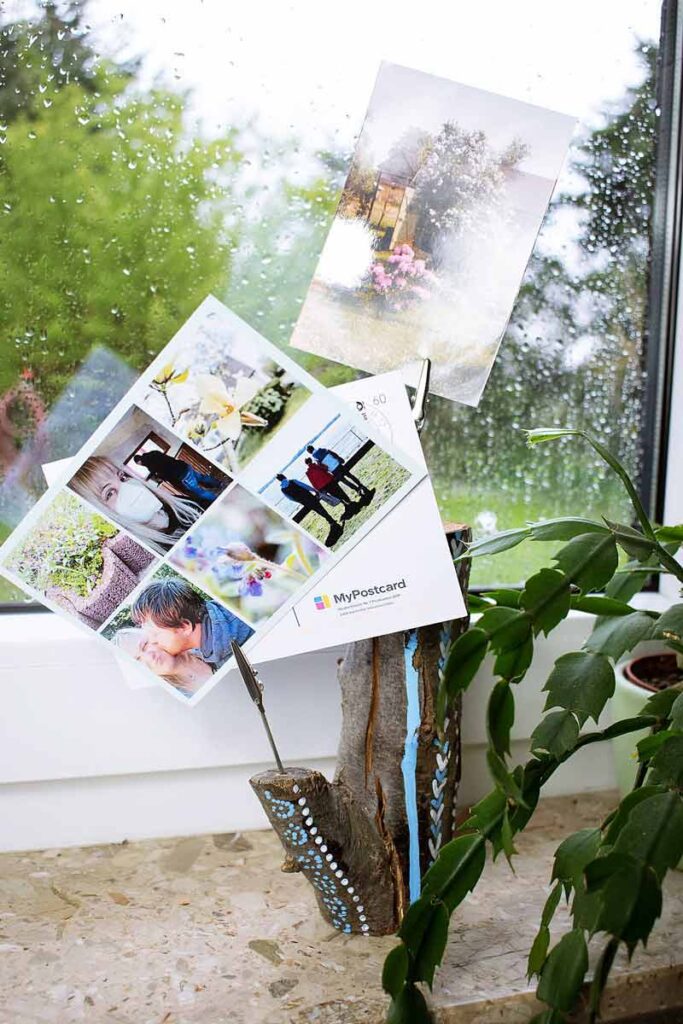 Der holz DIY Postkartebehalter liegt vor dem Fenster mit Postkarten in die Fotoklammern. 