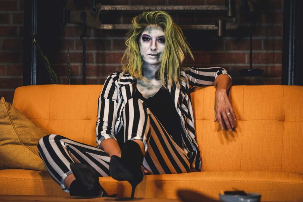 A woman in a Halloween outfit dressed like a dead prisoner on an orange sofa
