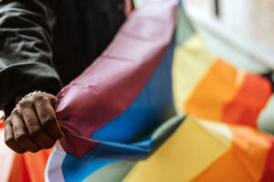 Ein Regenbogen Flagge wird dicht am Camera gehalten.