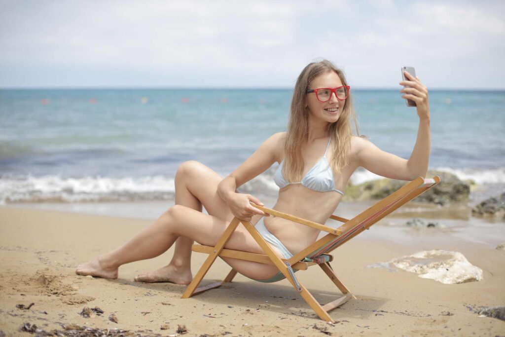 A girl confidently take a photo in a deck chair at the beach