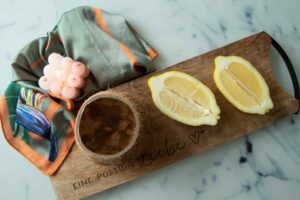 Two lemon shells and a cocount half sitting on a woode n board on a marble counter top
