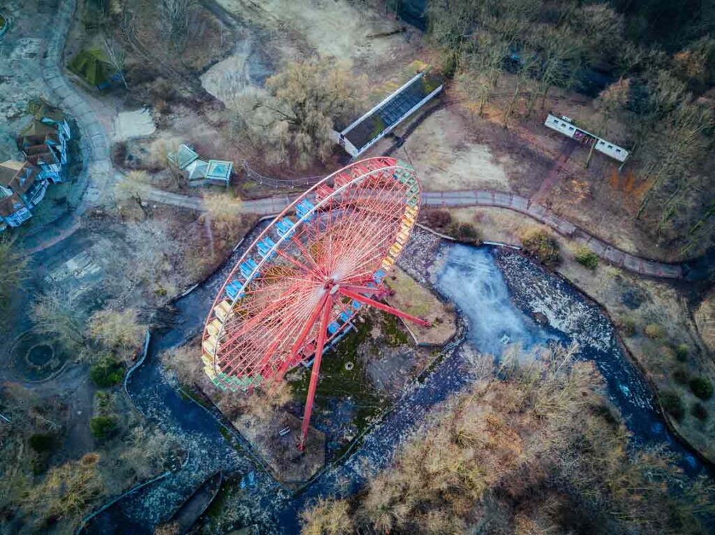 Vogelperspektive, rotes Riesenrad steht in einem verlassenen Park und wirkt total verlassen und gruselig