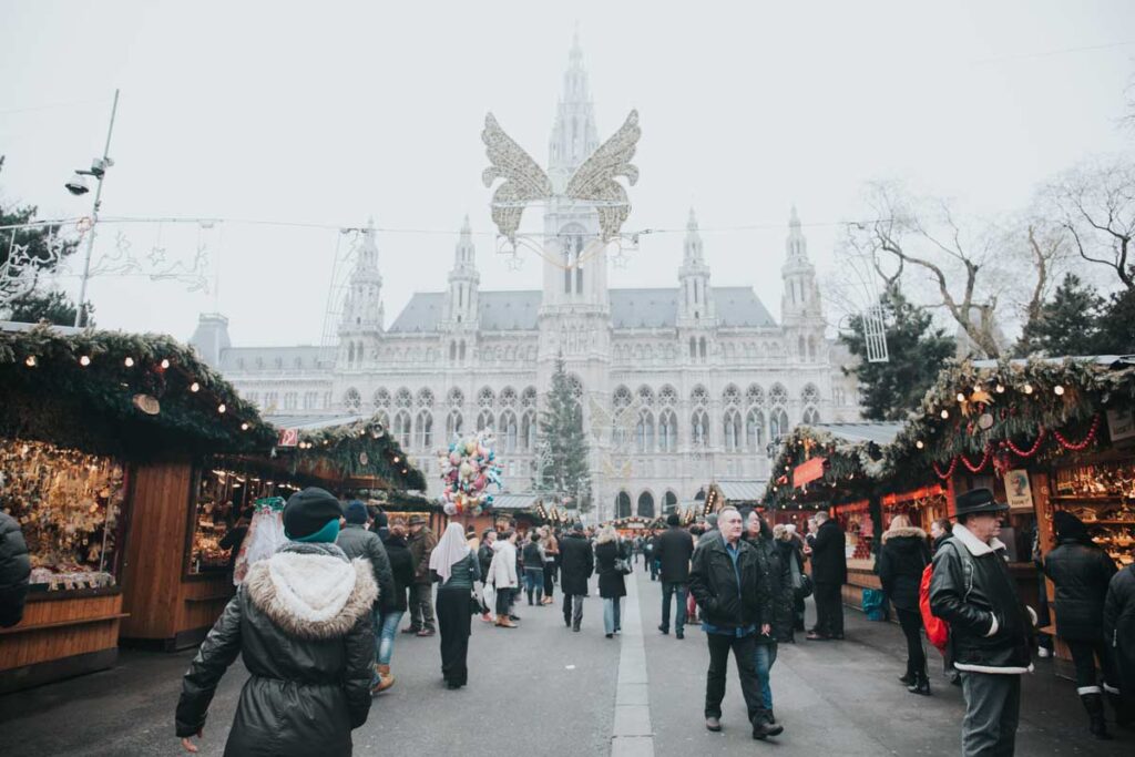 A Christmas market on a foggy day in positioned in front of a palace with festive decorations everywhere.