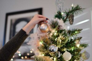 A hand hands a Christmas decoration on the tree,