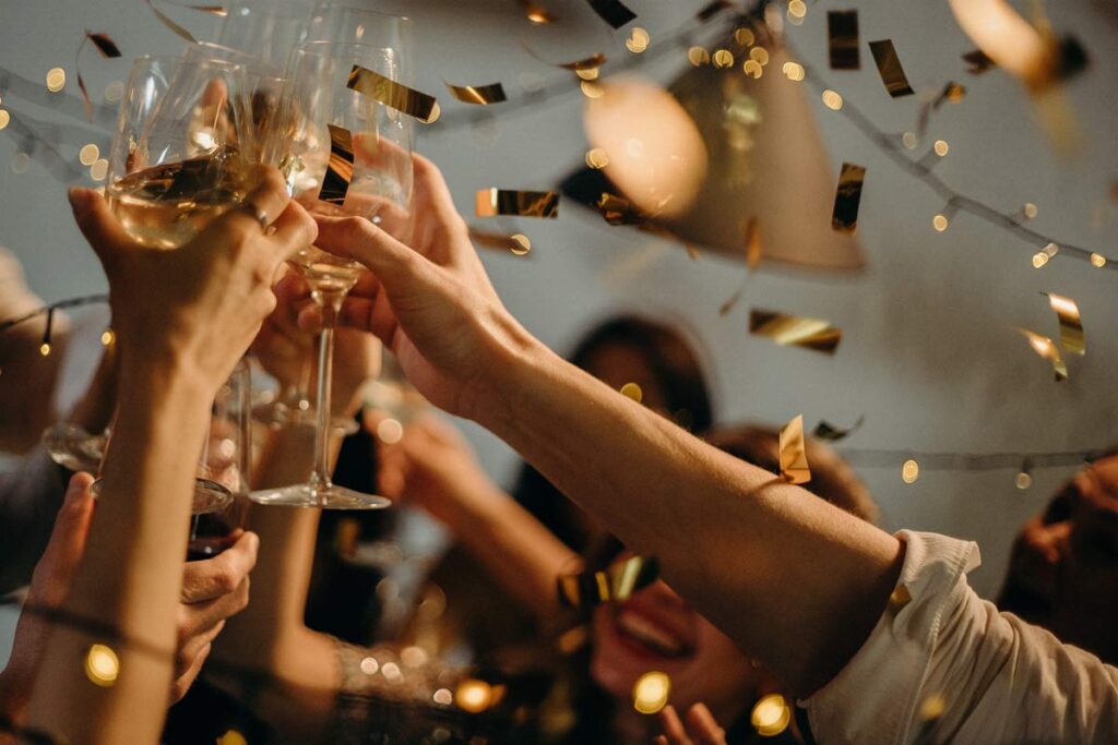 Hands clinking their champaign glasses together in the air celebrating New Year.
