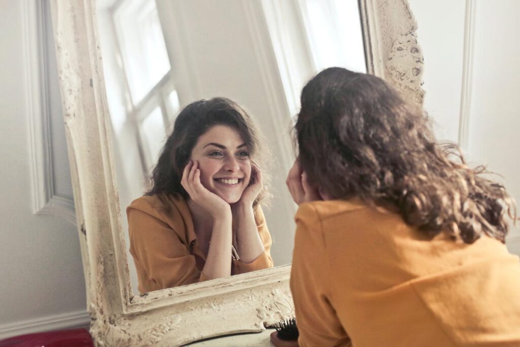 A woman smiles at herself in the mirror. 