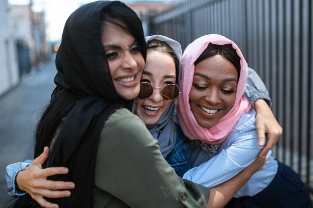 A group of three friends laughing and hugging out on the street