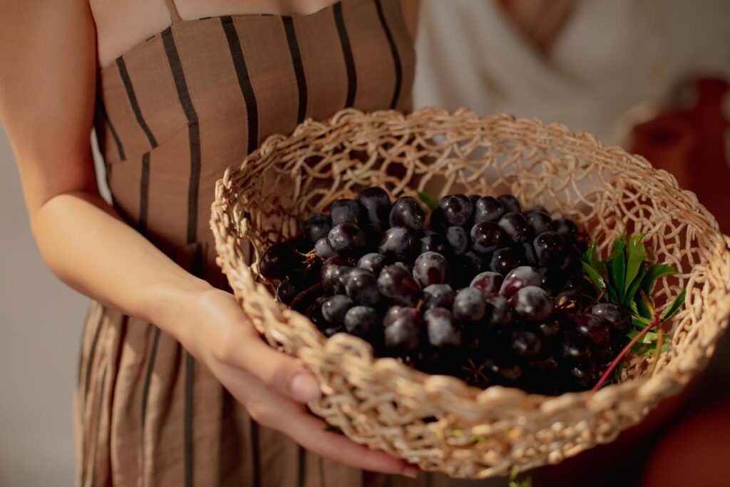 A close up of a woman holding a basket of black grapes as a New Year's Day tradition to eat 9.