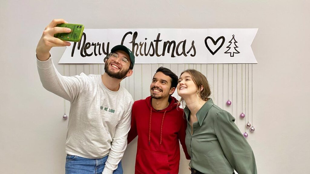 3 people taking a selfie underneath the Christmas DIY photobooth