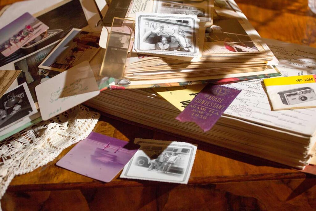 Memorabilia saved from past travels lie scattered on top of old books like coasters and postcards